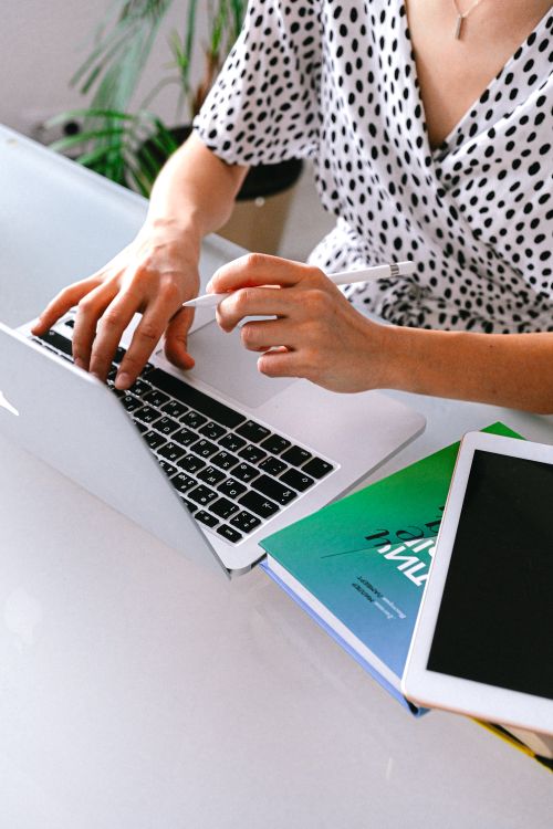 Free Woman in a home office using a laptop and tablet for remote work. Stock Photo