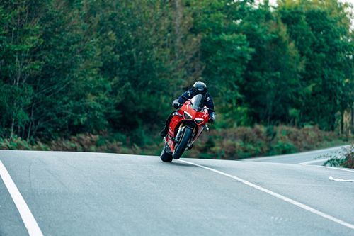 Free A dynamic scene capturing a red motorcycle racing down a forest road. Stock Photo
