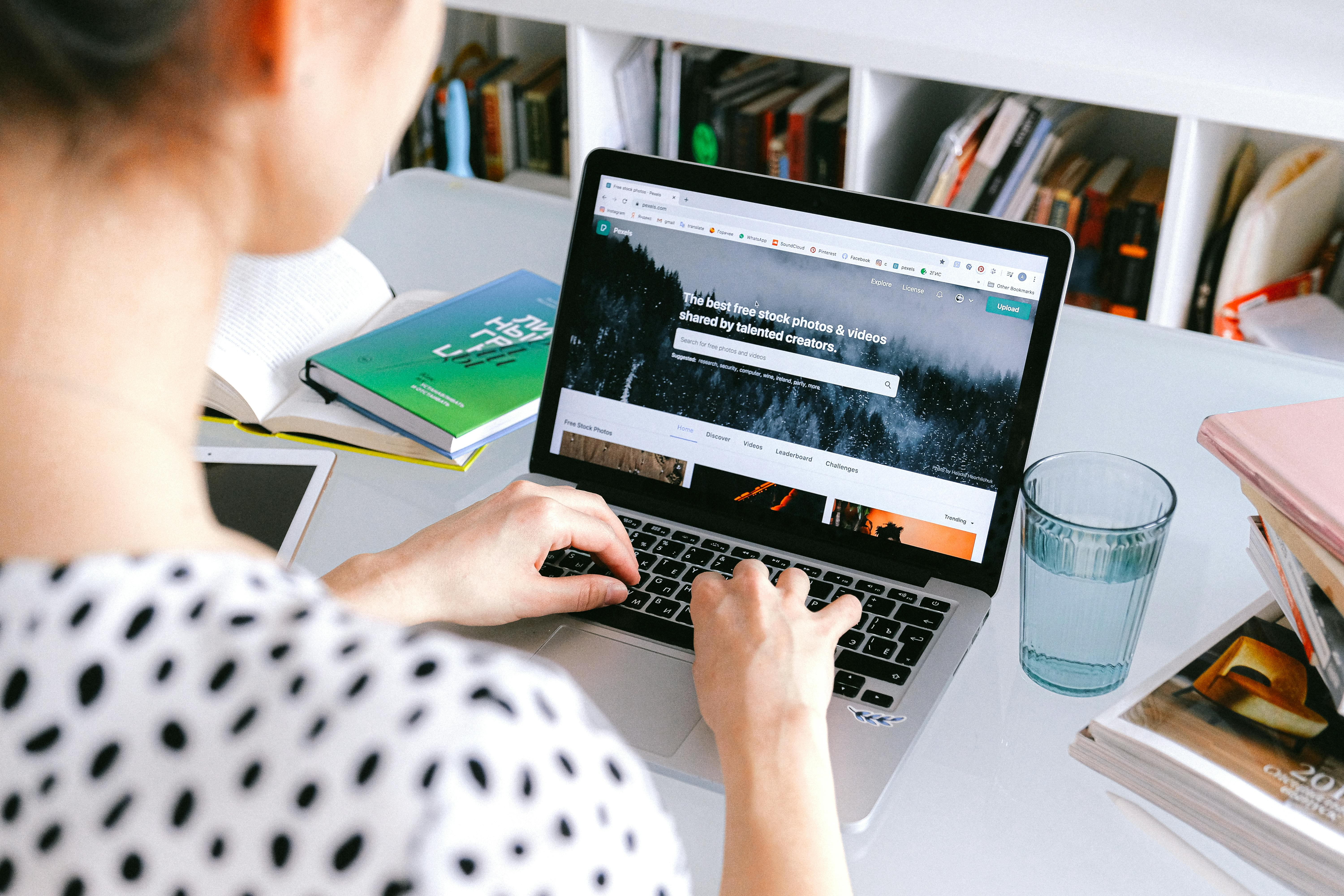 person using macbook pro on white table