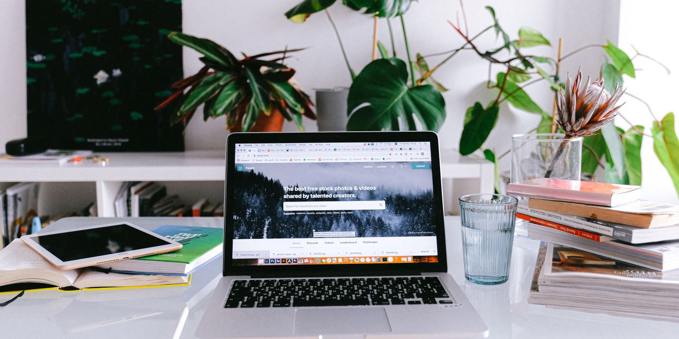 A clean and bright home office desk with a laptop, books, and plants, perfect for freelancers or remote work.