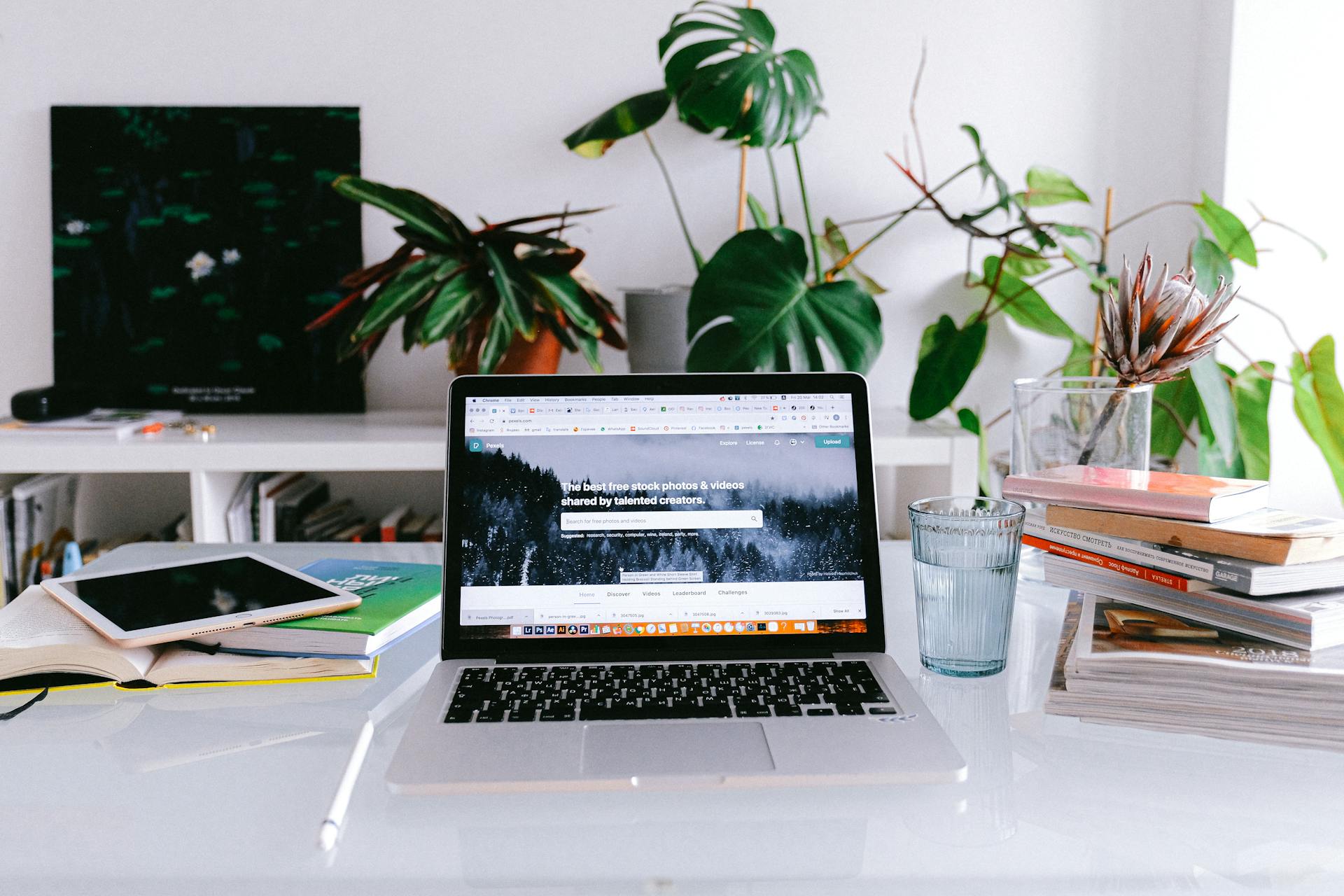 A clean and bright home office desk with a laptop, books, and plants, perfect for freelancers or remote work.