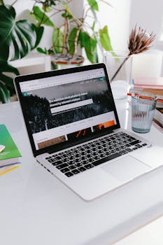 这张家庭办公室的桌子布置得很时尚，上面放着一台笔记本电脑，周围环绕着植物，营造出一种平静的居家办公氛围