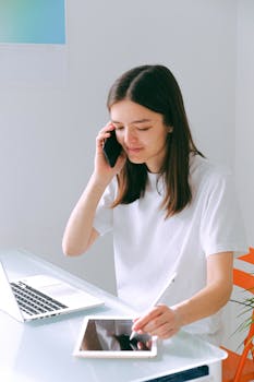 Young woman using technology for remote work at home office with laptop and tablet.