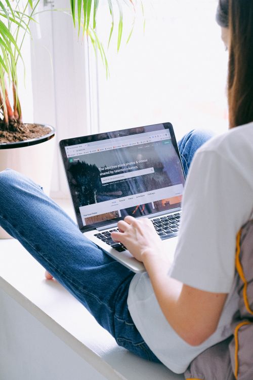 Free Young woman comfortably working on a laptop indoors, symbolizing remote work lifestyle. Stock Photo