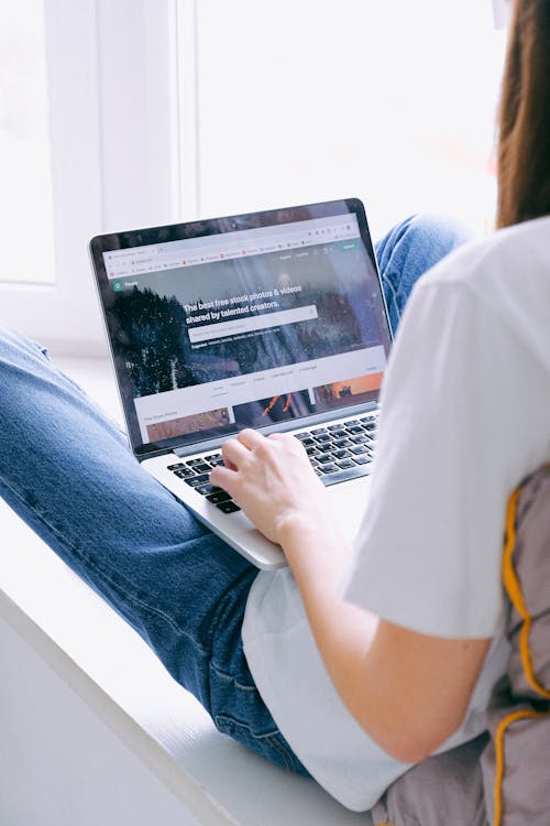 Free Person in Blue Denim Jeans Using Laptop Stock Photo