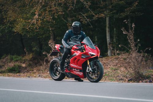 Free A motorcyclist on a red Ducati Corse riding through a scenic forest road. Stock Photo