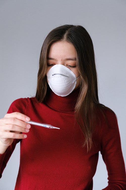 Woman in Face Mask Checking Thermometer