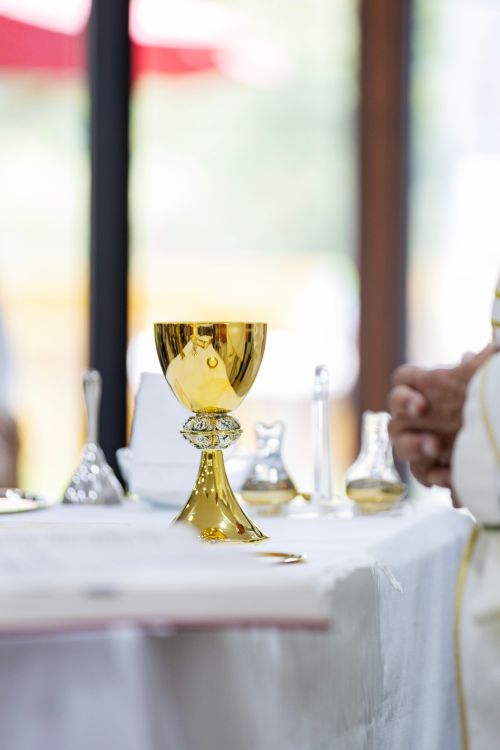 Free A golden chalice sits on an altar table during a religious ceremony with blurred background. Stock Photo