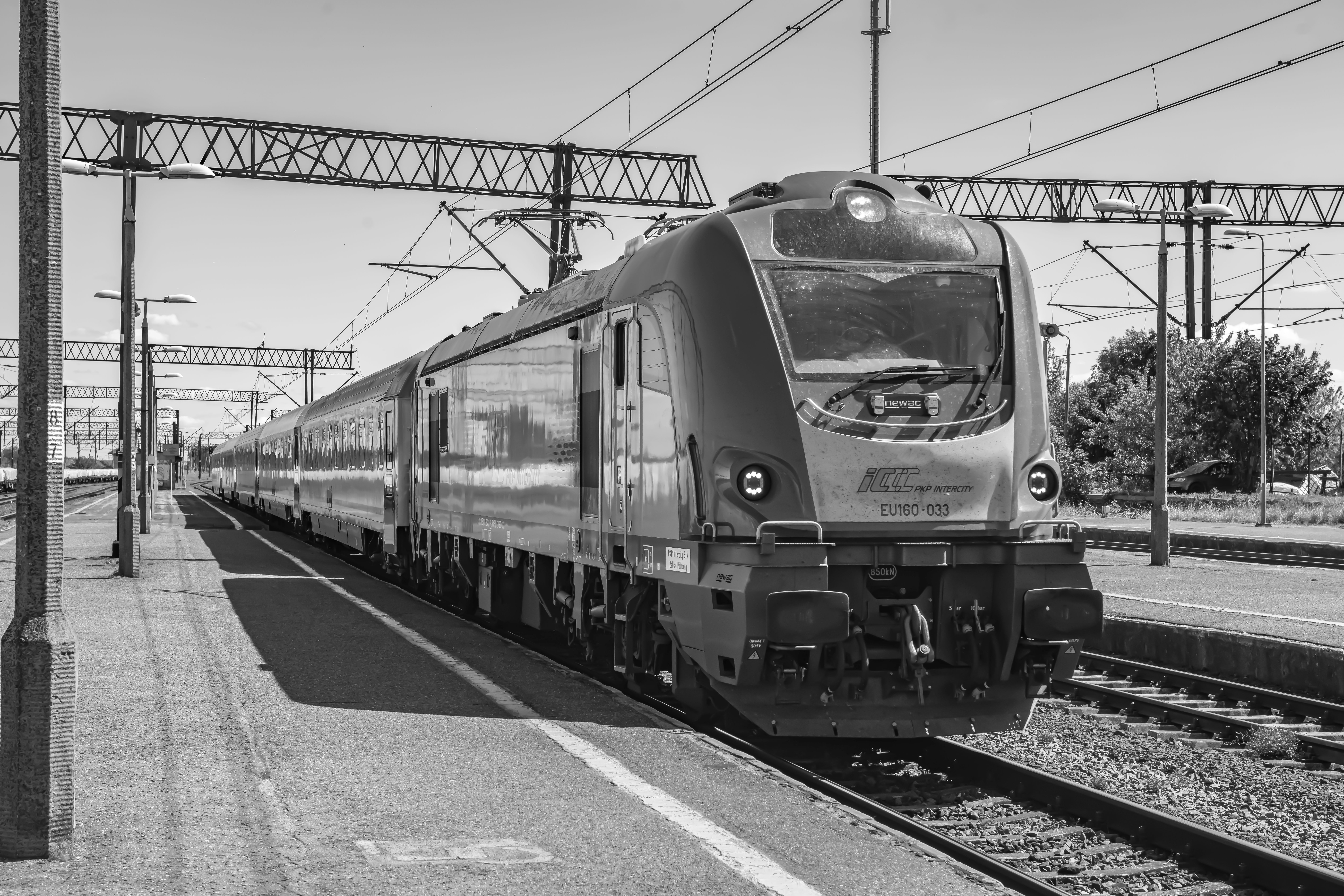 Modern train at a station platform captured in black and white.