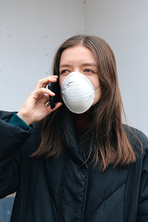 Woman in Face Mask Using Smartphone