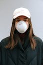这是一幅年轻女子的肖像，她戴着口罩和棒球帽，强调了疫情期间健康与防护的重要性