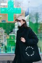 一个女人在药房前戴着口罩提着一个袋子
