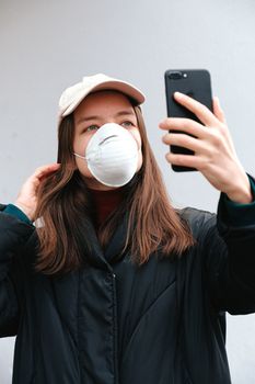 一名年轻女子戴着口罩在户外自拍，以在大流行期间促进健康和安全