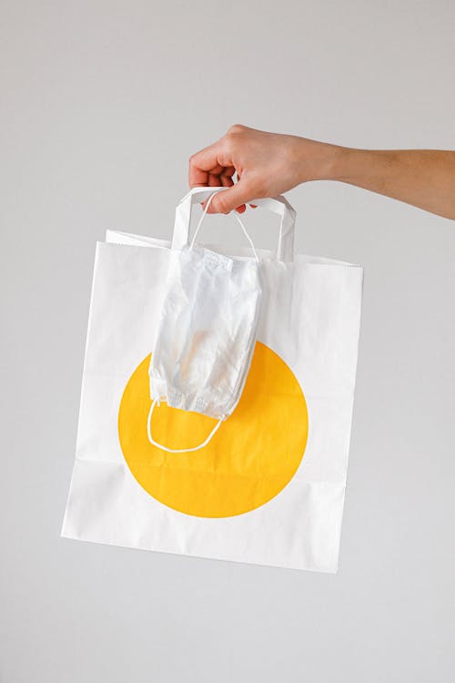 Free Person Holding Paper Bag and Face Mask Stock Photo