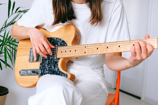 Close-up of a woman strumming an electric guitar indoors, showcasing her musical passion.