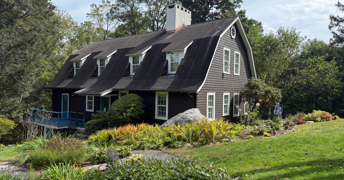 Beautiful colonial-style house surrounded by lush gardens and serene trees in a vibrant outdoor setting.