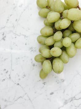 光滑的大理石表面放着一堆新鲜健康的绿色葡萄，非常适合营养主题