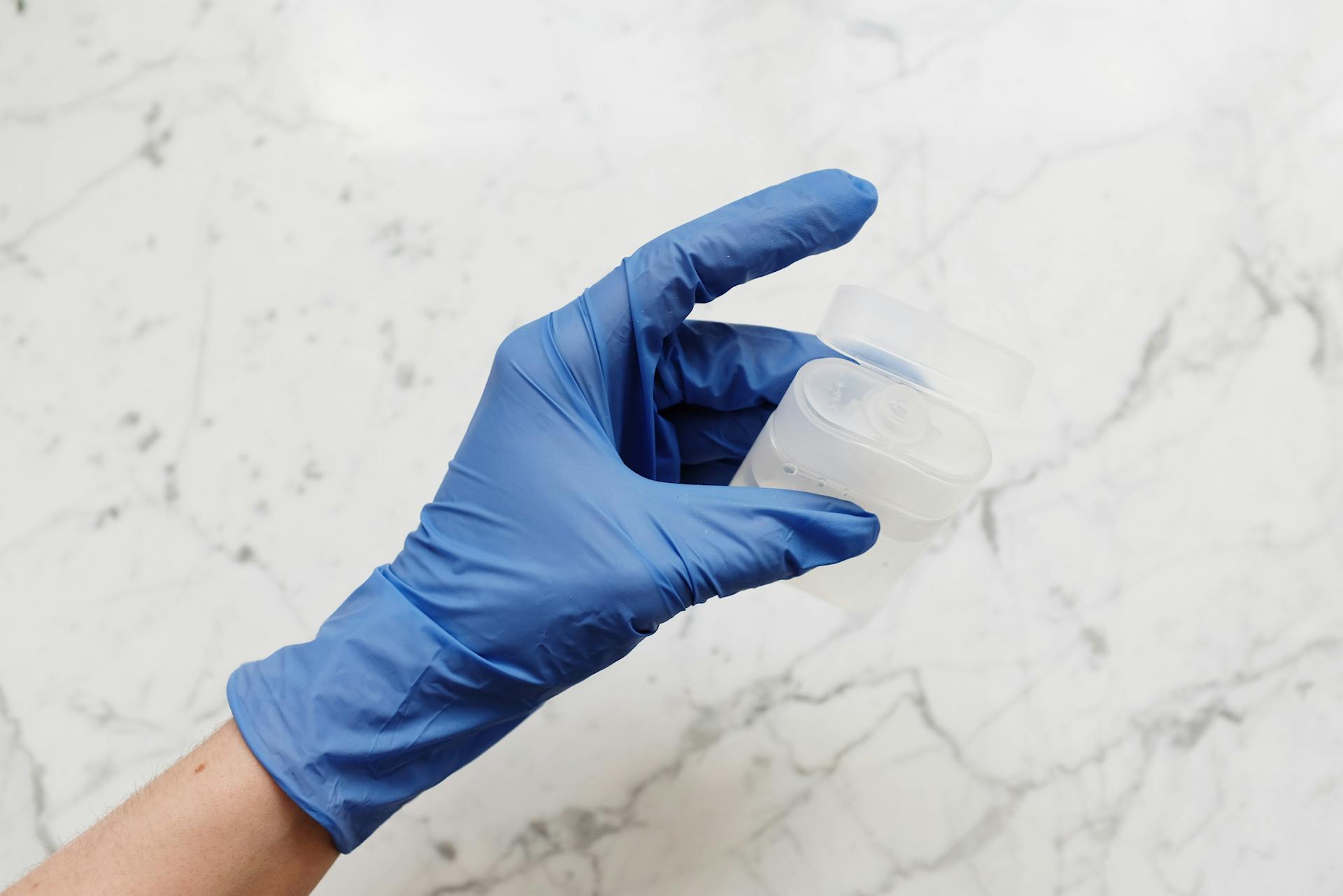 Person in Blue Gloves Holding Clear Plastic Container
