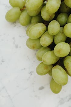 Bunch of green grapes displaying freshness and healthy nutrition on a marble top.