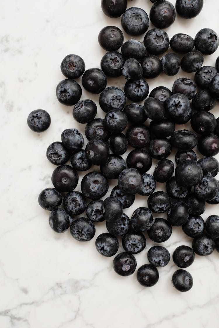 Black Round Fruits On White Ceramic Plate