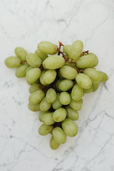 A detailed image of juicy green grapes on a marble surface showcasing freshness and organic appeal.