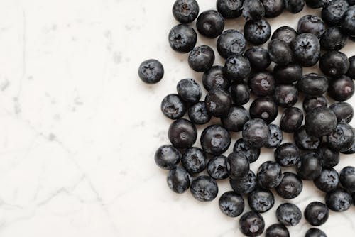 Black Round Fruits on White Surface