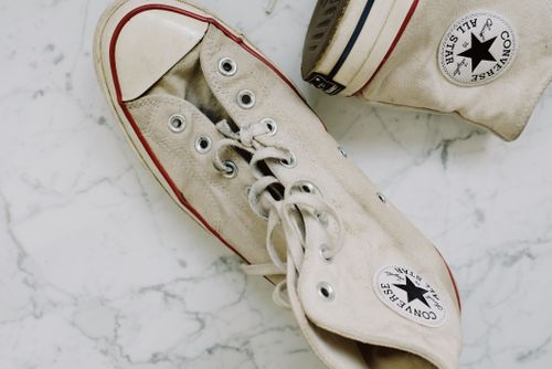 Free Classic Converse sneakers with a worn design on a marble surface, top view. Stock Photo