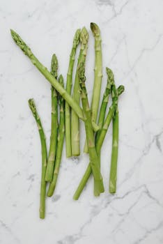 Vibrant green asparagus spears laid out on a marble countertop, showcasing freshness.