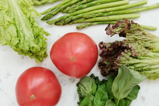 Close-up of fresh vegetables including lettuce, tomatoes, and asparagus for healthy cooking.
