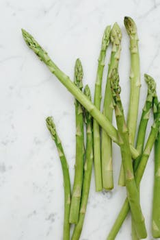 Close-up of fresh green asparagus stalks on a marble surface, highlighting healthy eating.