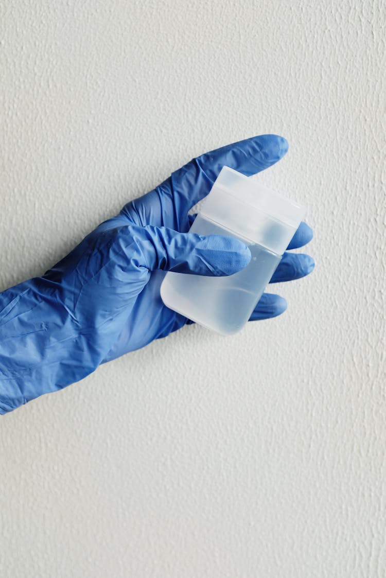 Person In Blue Gloves Holding White Plastic Bottle