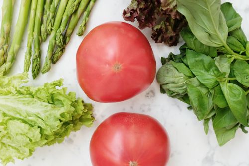 Free A vibrant collection of fresh vegetables including tomatoes, asparagus, and leafy greens on a marble surface. Stock Photo