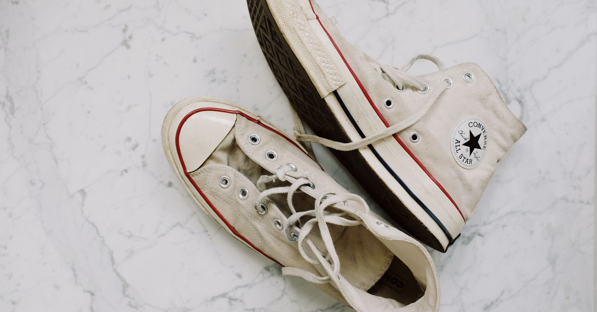 Um par de tênis Converse All Star sujos sobre uma superfície de mármore. Calçado com estilo vintage e na moda.