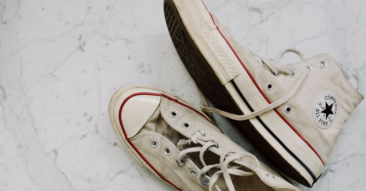 Close-up de tênis Converse All-Star usados em um piso de mármore para um estilo de moda vintage.
