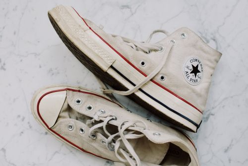 Free A pair of vintage Converse sneakers on a marble surface, showcasing classic style. Stock Photo