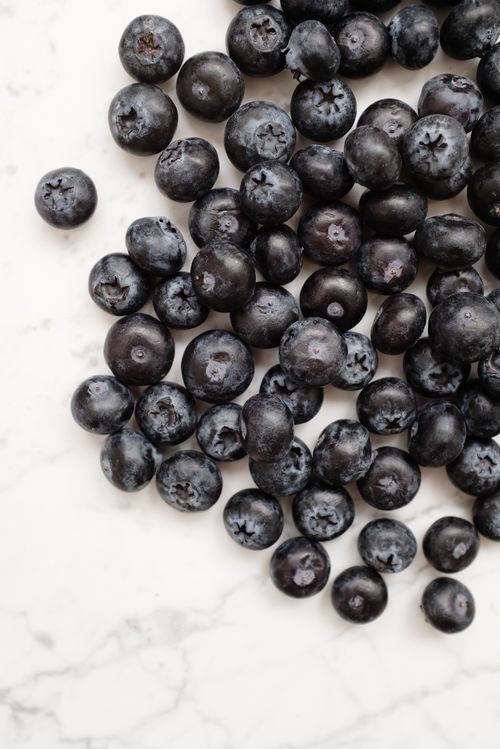 Free A close-up of fresh blueberries scattered on a marble surface, highlighting their natural freshness. Stock Photo
