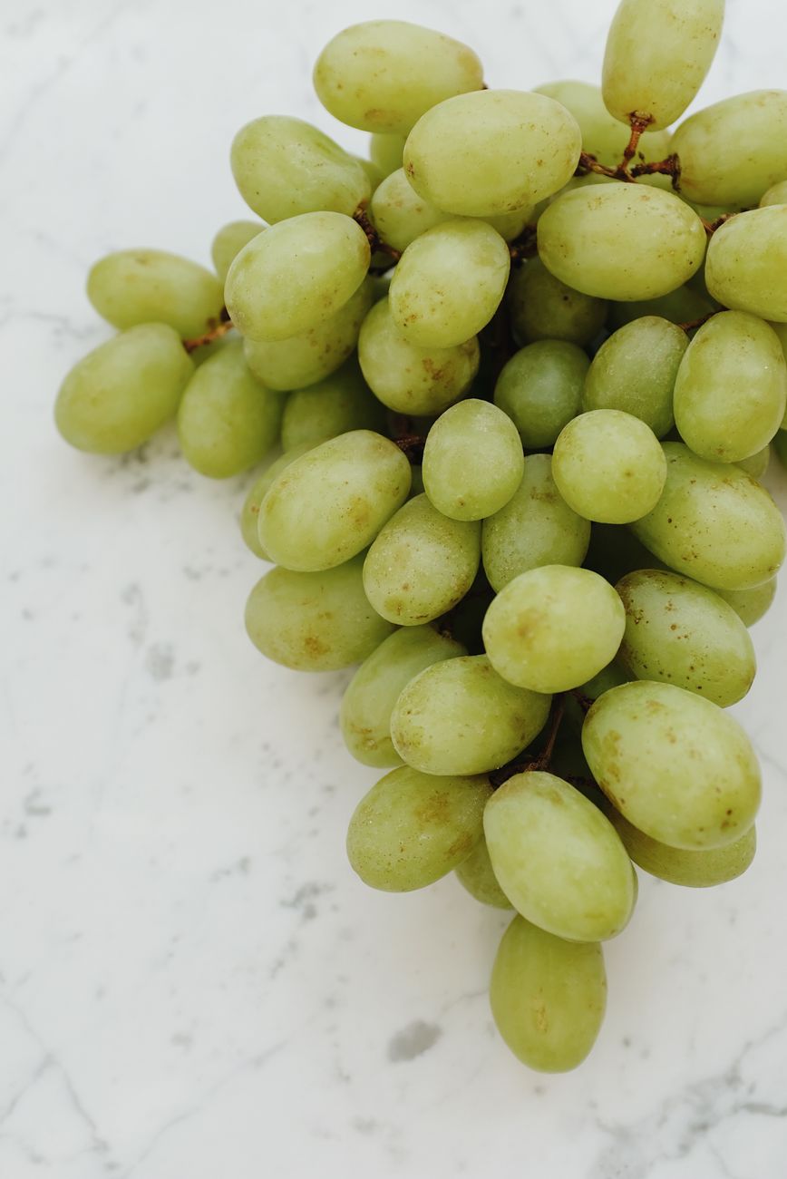 Green grapes on a marble surface show the ordinary food at the centre of the blood-pressure evidence, not a specialized supplement
