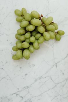 A bunch of fresh green grapes on a marble surface, perfect for health and nutrition themes.