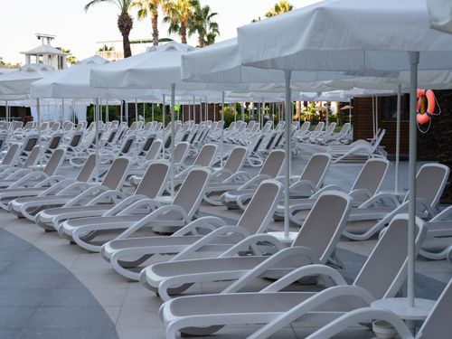 Free Elegant poolside loungers and umbrellas by the resort pool, perfect for a relaxing vacation retreat. Stock Photo