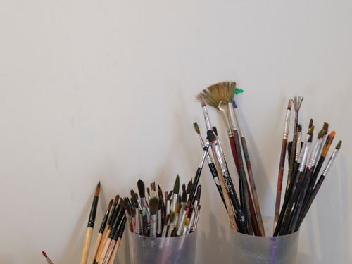 Free Close-up of various paintbrushes set in holders against a white wall in an artist's workspace. Stock Photo