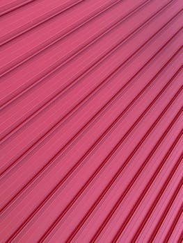 Pink corrugated metal surface showcasing textured lines and patterns for background or design use.