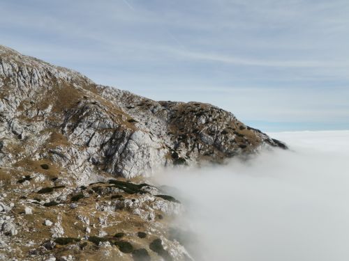 Free A breathtaking view of a rugged mountain peak emerging above a sea of clouds under a clear sky. Stock Photo