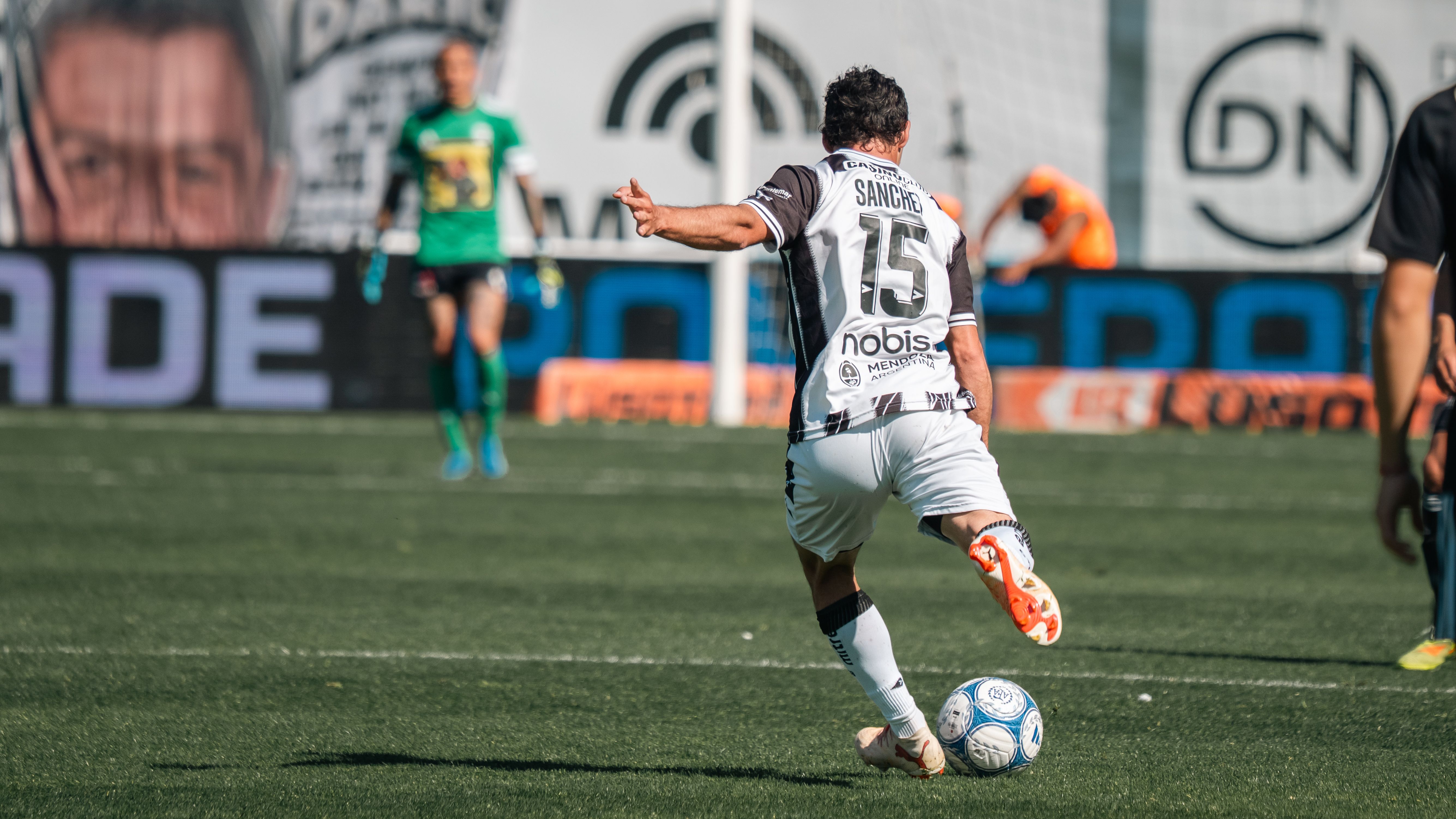 Action shot of a soccer player wearing jersey number 15 kicking the ball on the field.