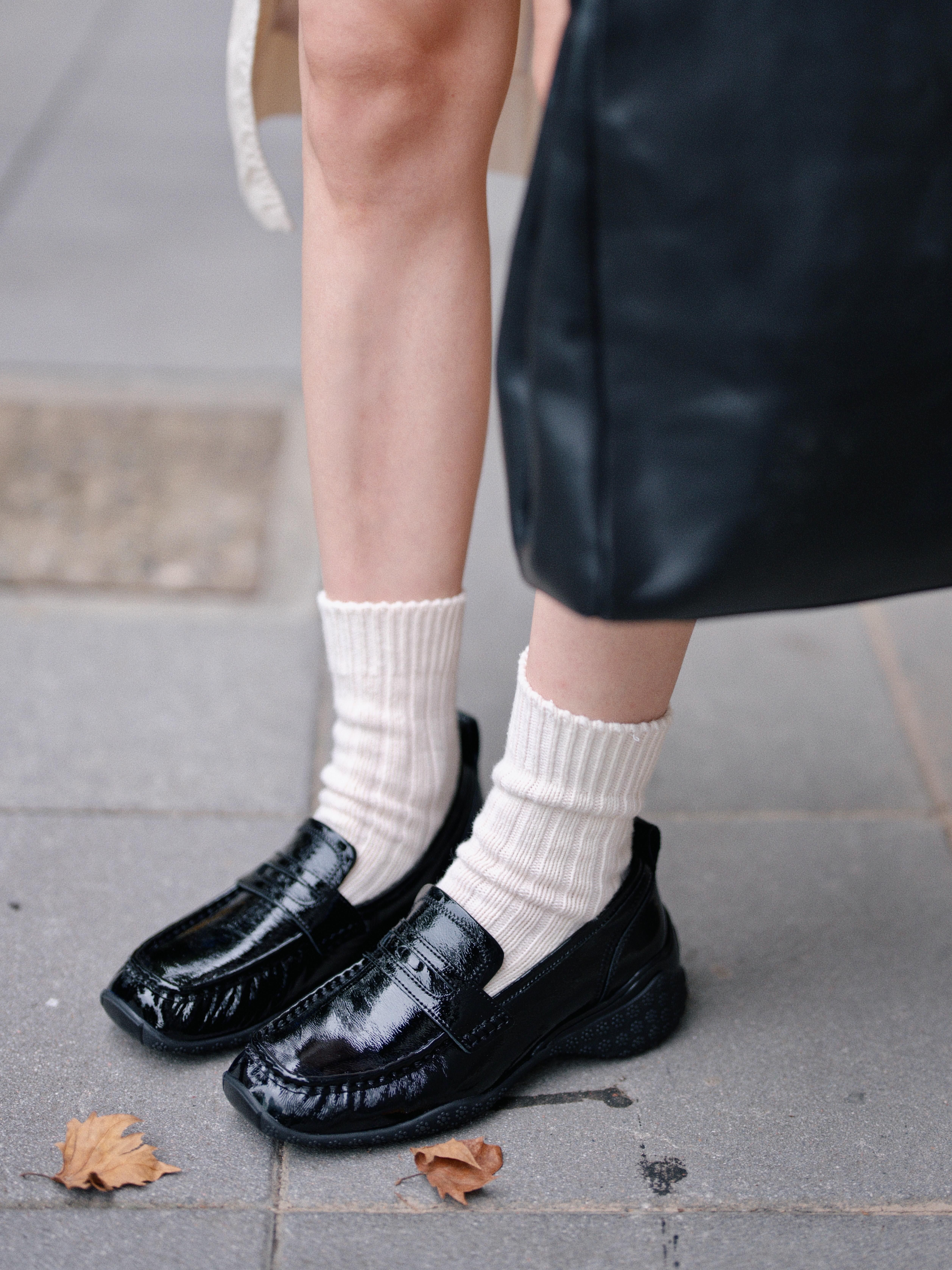 Stylish black loafers paired with white socks on an urban sidewalk in Shanghai.