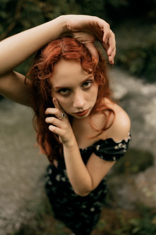 Free Portrait of a young woman with red hair in a natural outdoor setting, displaying elegance and mystique. Stock Photo