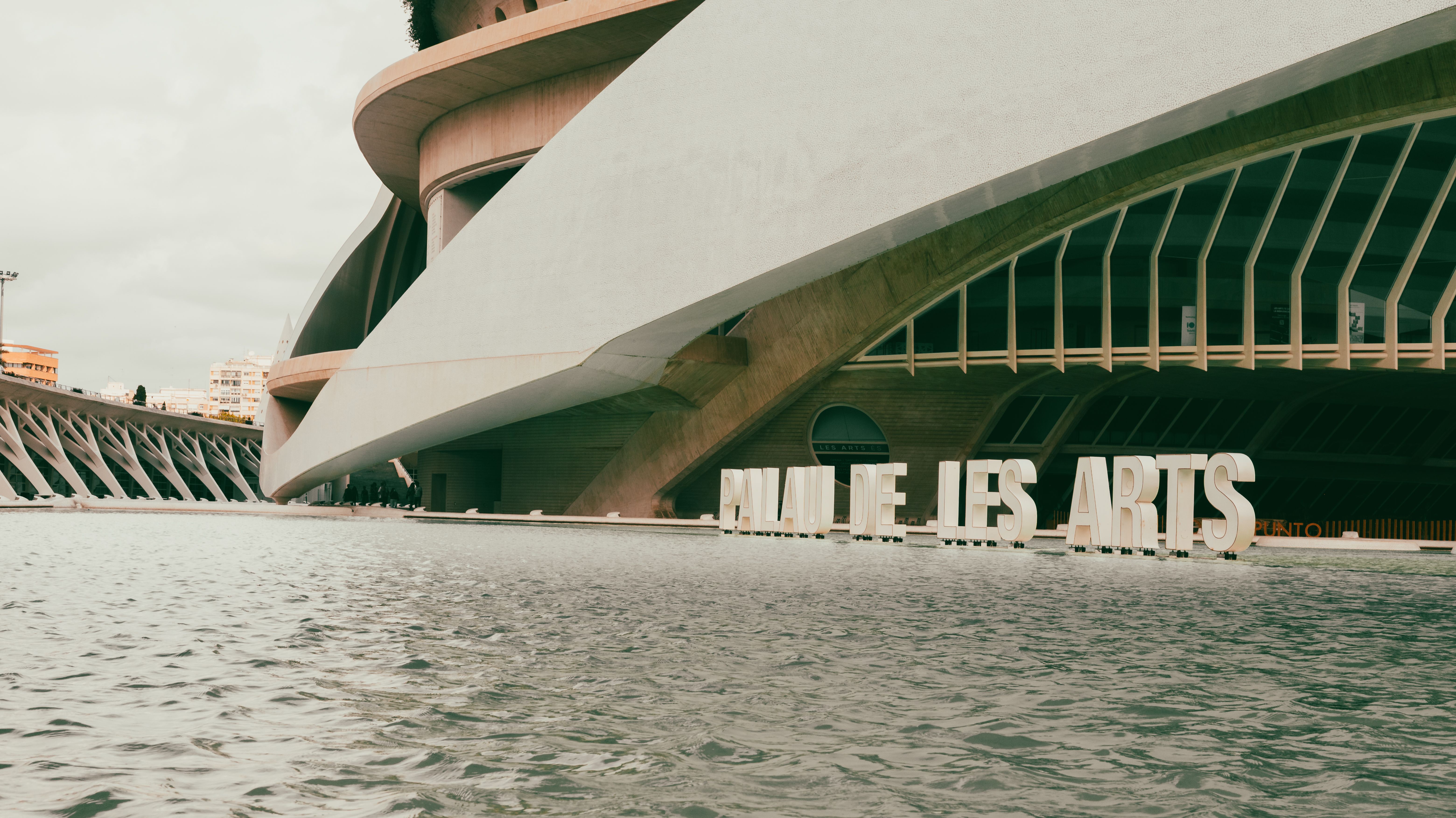 Sleek modern architecture of Palau de les Arts in Valencia, Spain with serene water foreground.