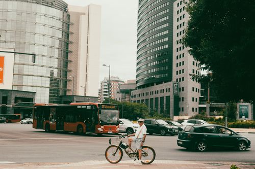 Free A bustling city intersection with a cyclist, traffic, and towering skyscrapers creating a dynamic urban scene. Stock Photo