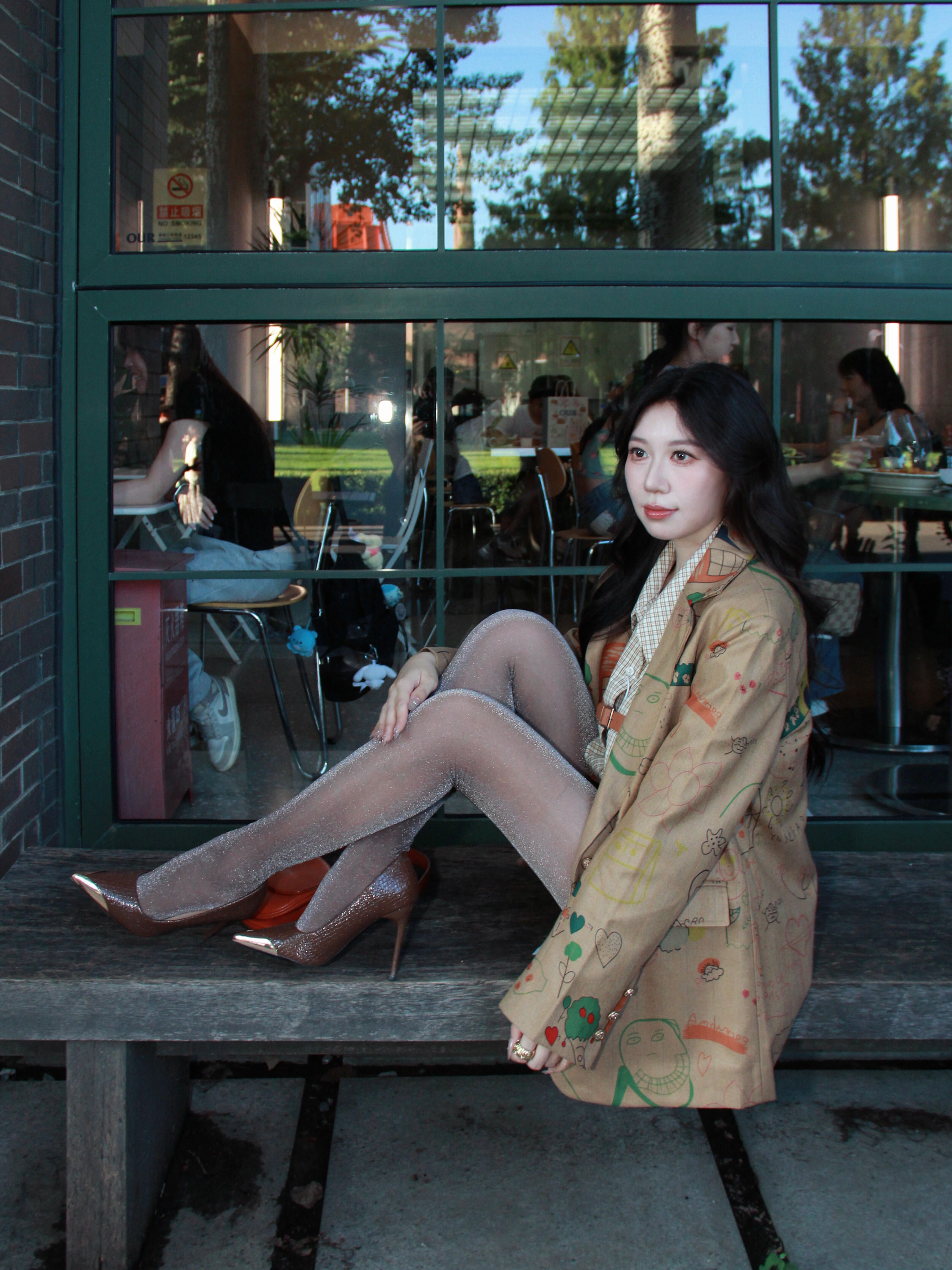 A fashionable woman in silk stockings sits on a bench outside a Beijing cafe. Casual and urban fashion vibe.
