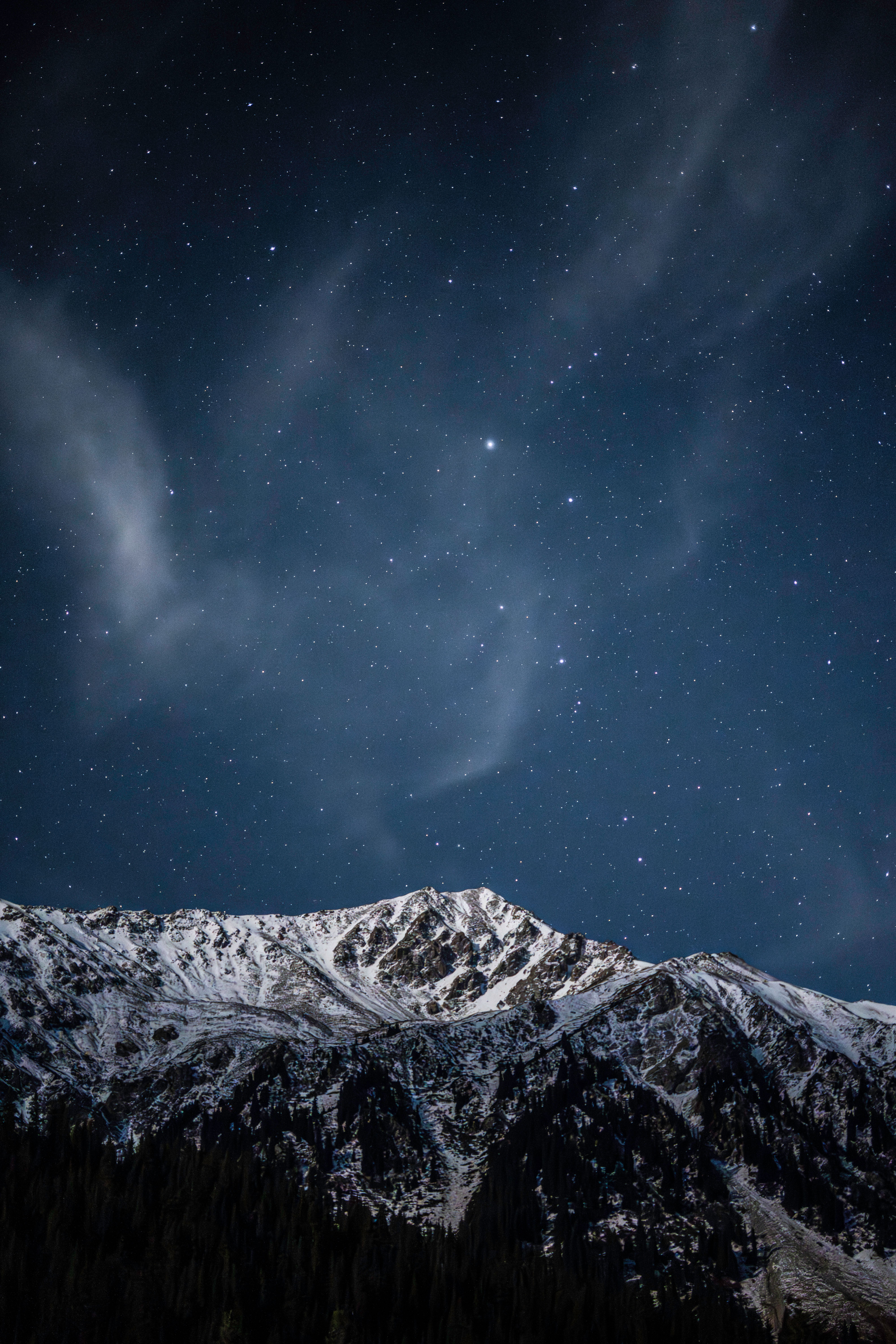 A breathtaking view of a snowy mountain range under a star-filled night sky in Kyrgyzstan.