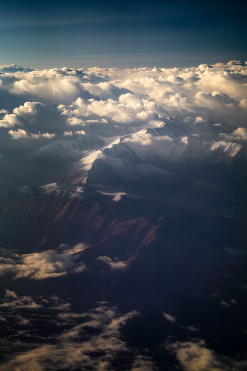 Free Breathtaking aerial shot of snow-covered mountains blanketed in clouds in Kyrgyzstan. Stock Photo